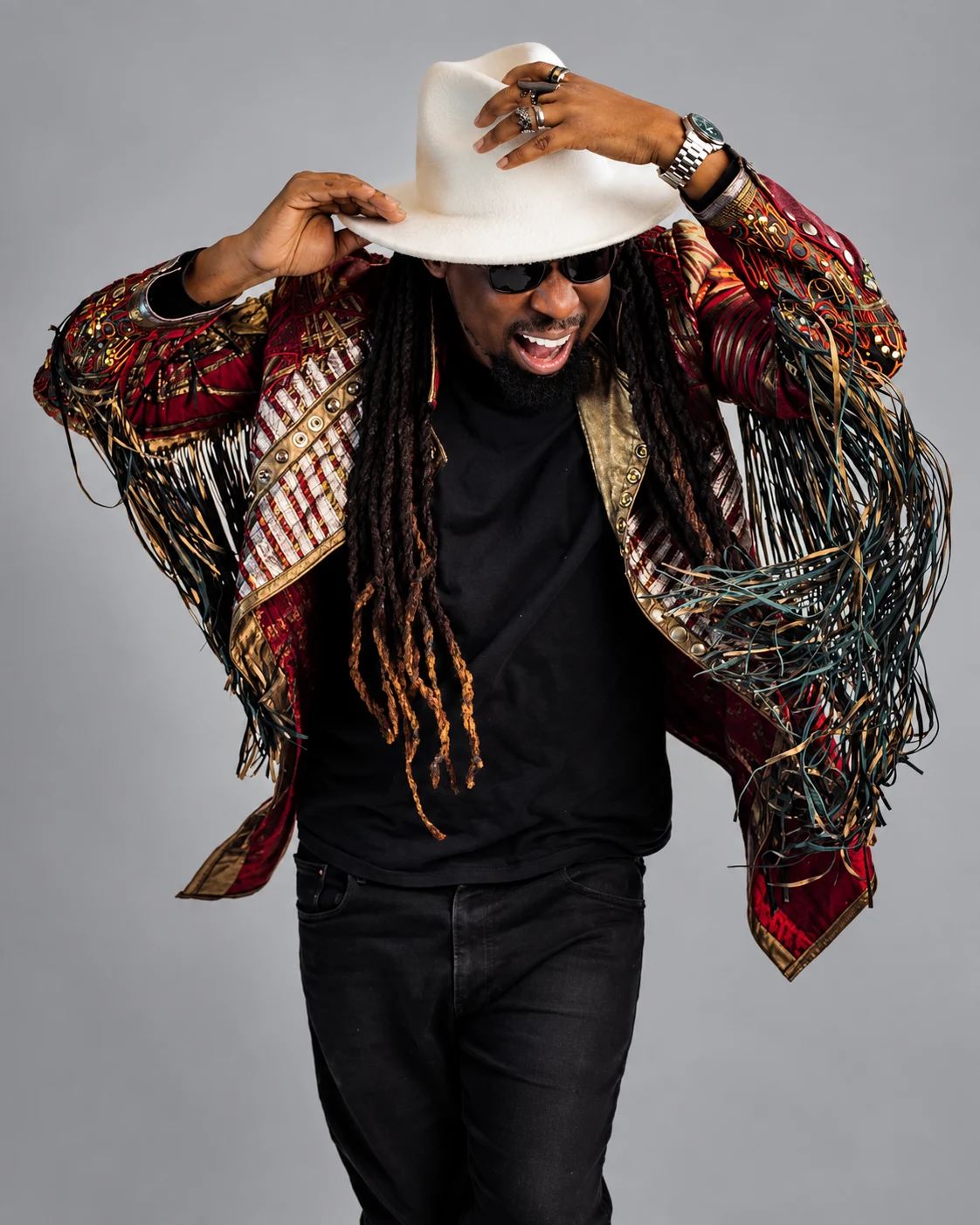 Brayo Bryans smiling in a patterned jacket and pale hat during a studio portrait session